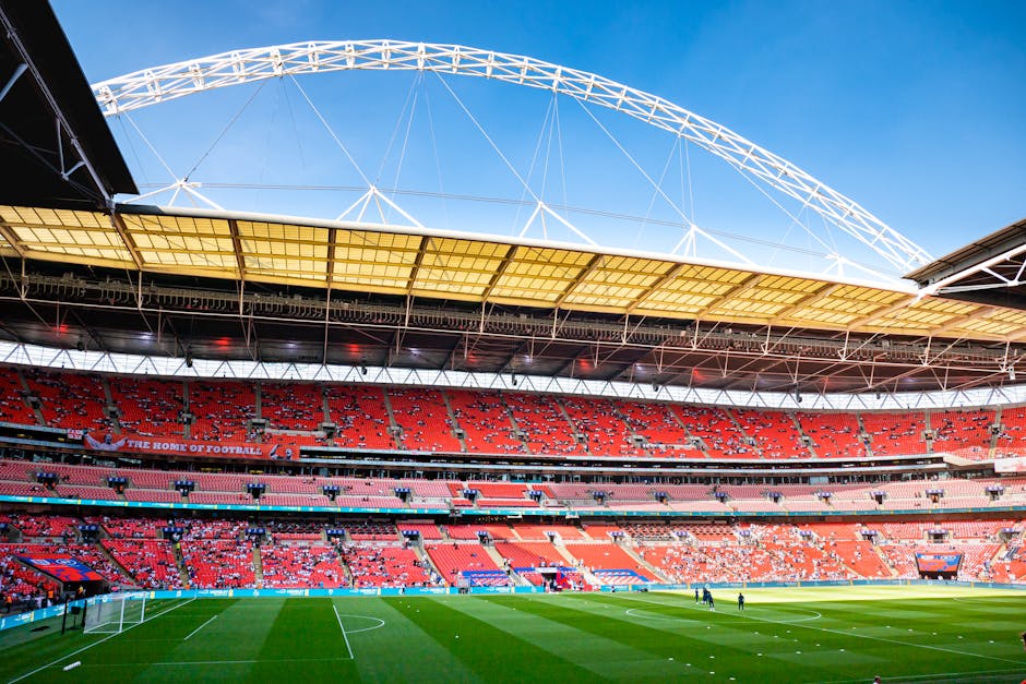 A wide shot of an urban outdoor staircase leading up to Wembley Stadium, with brightly painted steps featuring colorful murals of people engaging in various activities. The staircase is flanked by mod